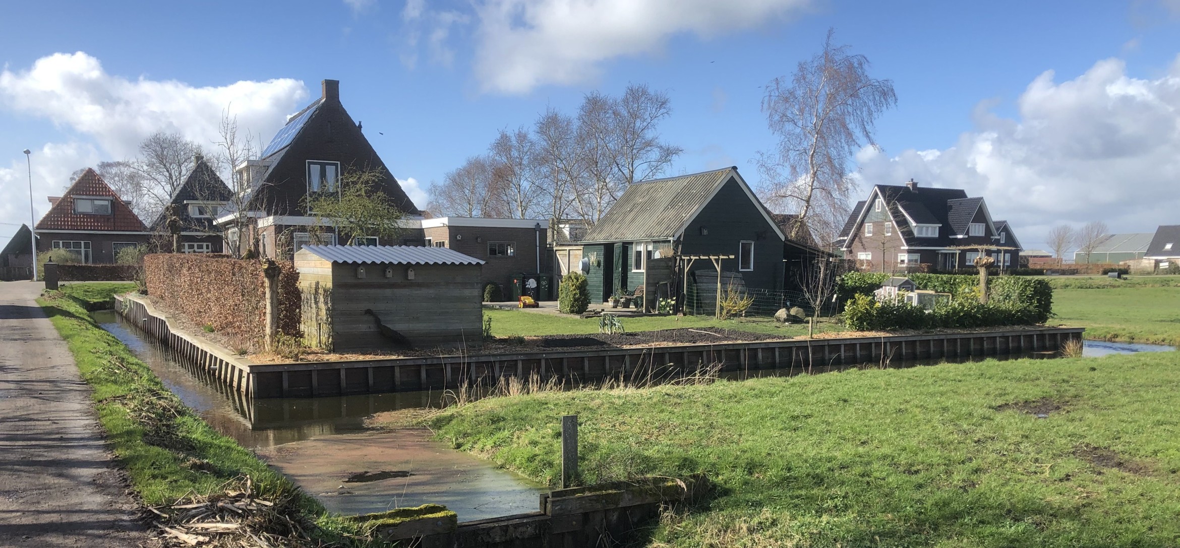 Foto van rij met woningen aan de achterzijde met een hoogwatervoorziening erbij